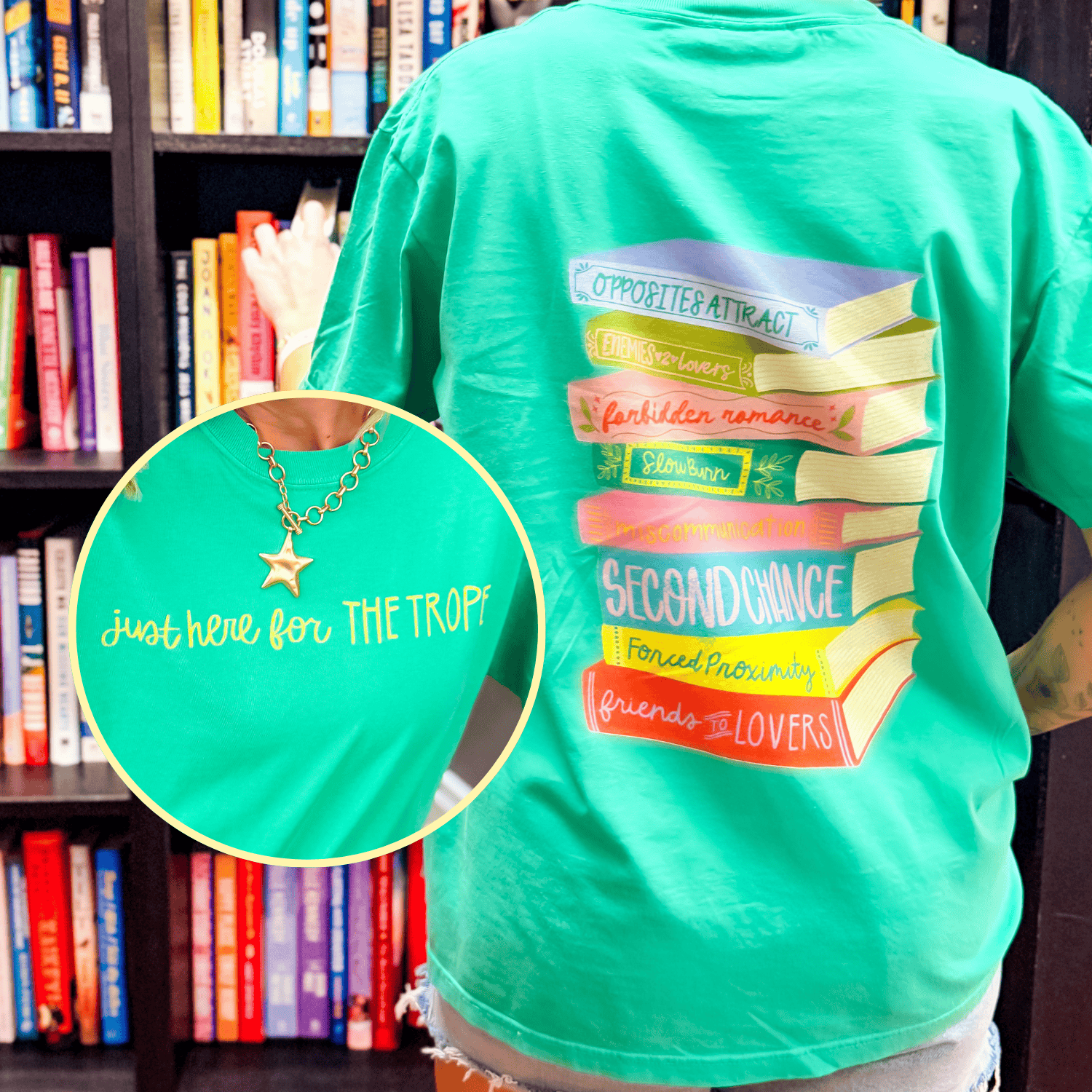 Just Here For The Tropes tee in bright green, featuring colorful book graphics and text on the back.