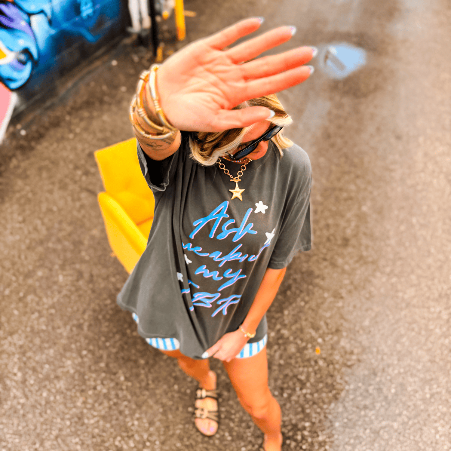 Gray T-shirt with "Ask Me About My TBR" text in blue, worn by a person in a casual setting with a yellow chair.